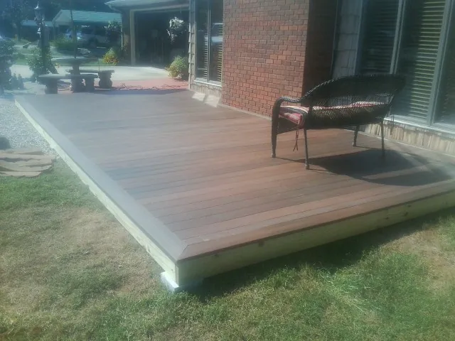 New wood deck and wicker chair beside a brick house in Houston
